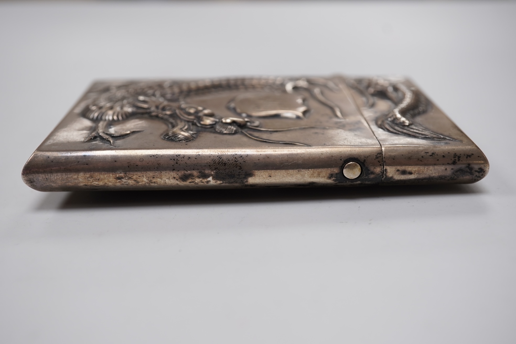 A late 19th century Chinese Export white metal card case, by Cum Shing, Canton, embossed with a dragon and applied shield shaped panel engraved with monogram, 90mm, 85 grams.